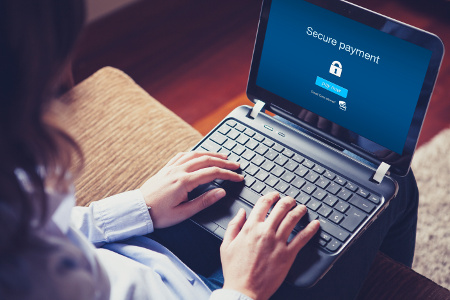 A woman typing on her laptop with a secure payment screen on the laptop